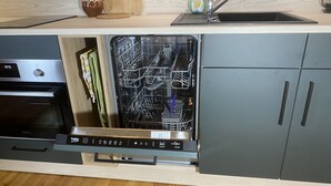 A kitchen with a built-in dishwasher, a sink, and a wooden countertop.