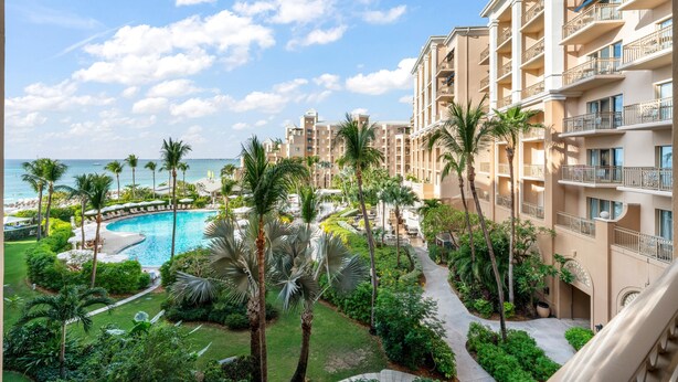 A resort with a pool, palm trees, and a view of the ocean. - Private Residence at The Ritz-Carlton Resort, Grand Cayman (Seven Mile Beach)
