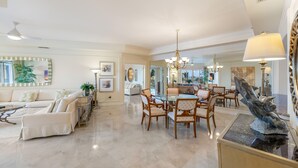 A spacious living room with a large dining table, comfortable seating, and a chandelier. - Private Residence at The Ritz-Carlton Resort, Grand Cayman (Seven Mile Beach)