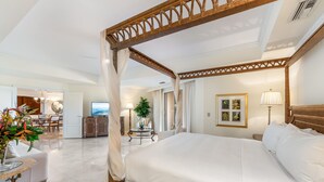 A spacious bedroom with a four-poster bed, a dining area with a chandelier, and a view of the sea. - Private Residence at The Ritz-Carlton Resort, Grand Cayman (Seven Mile Beach)