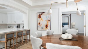 A modern kitchen with white cabinetry, a wooden dining table, and bar stools. - Sophisticated Ocean View Residence located at The Ritz-Carlton (Seven Mile Beach)