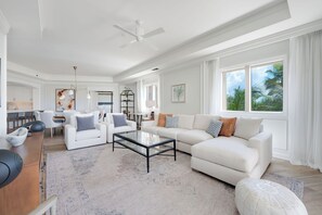 A spacious living room with a white sofa, a glass coffee table, and a dining area with a bar.