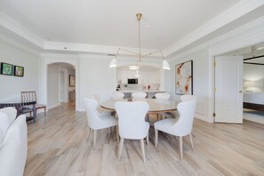 A modern dining area with a round table, white chairs, and a central light fixture.