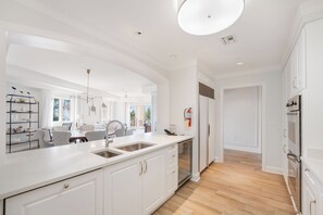 A modern kitchen with white cabinetry, a large island with a sink, and a view to the dining area.