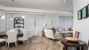 A spacious living room with a dining area, featuring a wooden floor, modern furniture, and a ceiling fan. - Sophisticated Ocean View Residence located at The Ritz-Carlton (Seven Mile Beach)