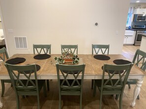 A dining area with a wooden table, six green chairs, and a 'Gather' sign. - Relax in our large 4b/2b ranch w/hot tub,firepit, game room, sleeps 11, pets ok (Sawyer)