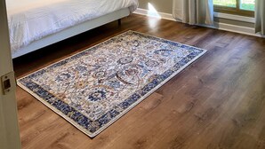 A bedroom with a bed, a ceiling fan, a large window with curtains, and a patterned rug. - Relax in our large 4b/2b ranch w/hot tub,firepit, game room, sleeps 11, pets ok (Sawyer)