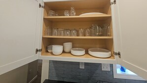 A kitchen cabinet with shelves holding glassware, plates, and bowls. - Relax in our large 4b/2b ranch w/hot tub,firepit, game room, sleeps 11, pets ok (Sawyer)