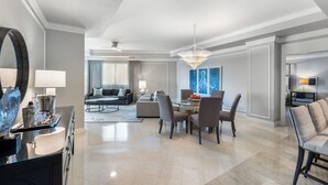 Ein modernes Wohnzimmer mit Essbereich, einem großen Spiegel und einer Chandelüster.