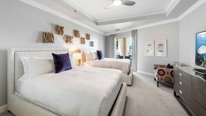 Ein Schlafzimmer mit zwei Betten, einem Deckenventilator, Kunstwerken an der Wand und einer Kommode.