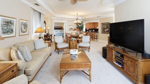 Un salon spacieux doté d’un grand téléviseur à écran plat, d’un ventilateur de plafond et d’un coin repas avec des meubles en bois.