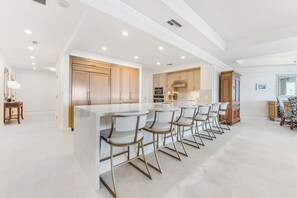 A modern kitchen with a central island, bar stools, and wooden cabinetry.