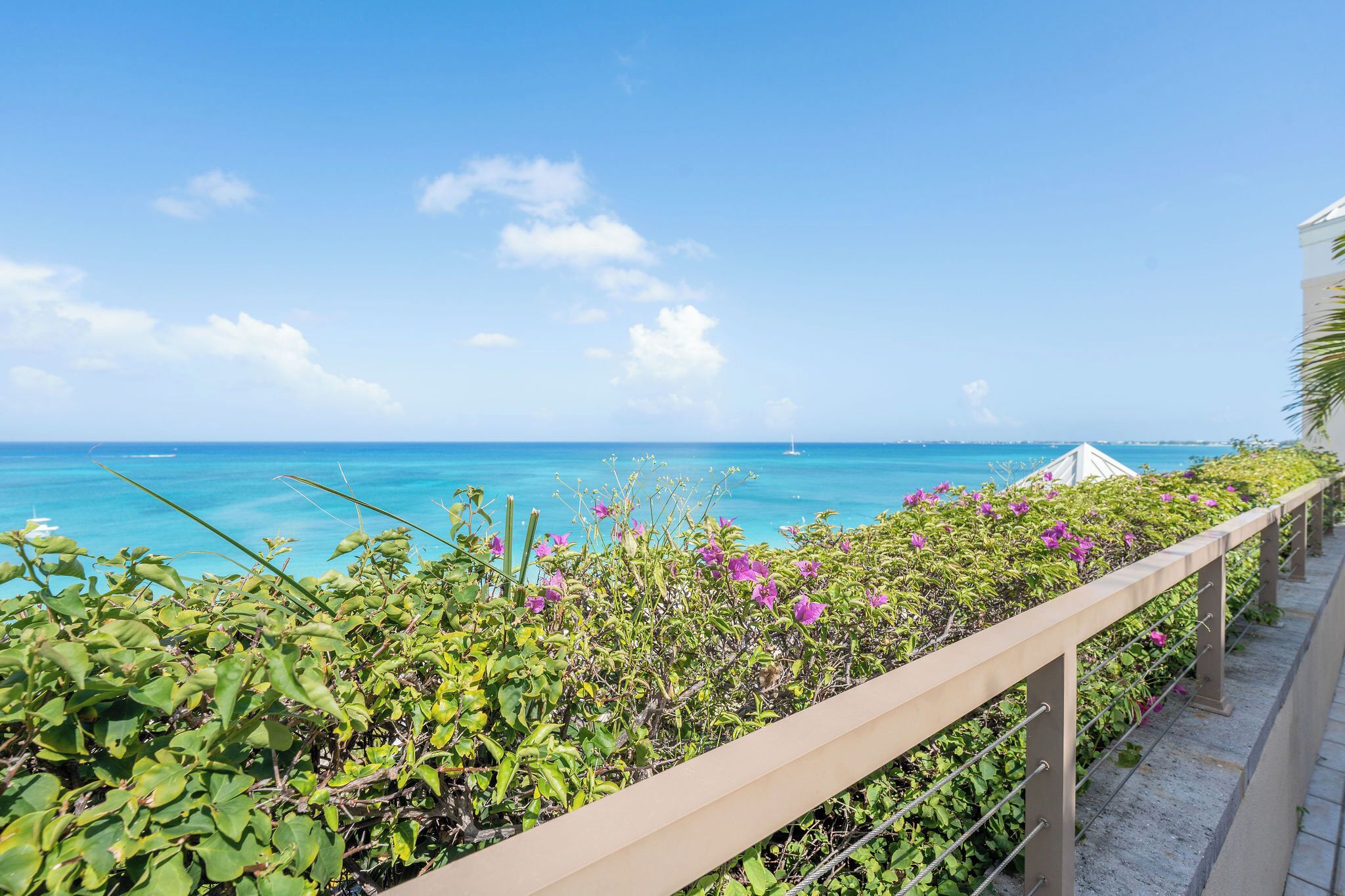 A coastal view with a clear sky, a railing, and a body of water.