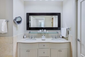Een badkamer met twee wastafels, een grote spiegel en een glazen plank met toiletartikelen.