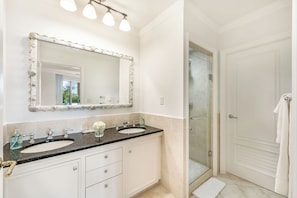 A bathroom with two sinks, a large mirror, and a shower area.