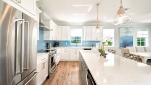 A modern kitchen with white cabinets, stainless steel appliances, and a large island.