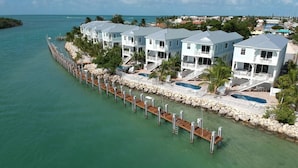 A waterfront property with multiple two-story buildings, a dock extending into the water, and a swimming pool.