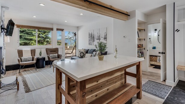 Una cocina moderna con una isla grande, vigas de madera y vistas al exterior.