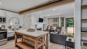 Una cocina moderna con una isla central, electrodomésticos integrados y una pared de acento de piedra.