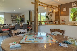 A dining area with a board game, wooden furniture, and a large window with a view of trees.