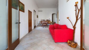 A hallway with a red sofa, a dining area, and a wooden sculpture.