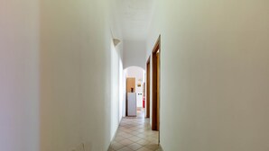 A narrow hallway with tiled flooring and white walls.