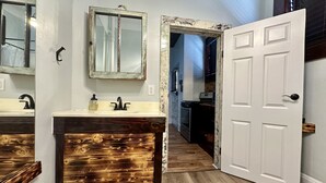 A bathroom with two sinks, a mirror, and a door leading to a kitchen. - Pet friendly 1bd/1b unit with full kitchen and dining area (Gainesville)