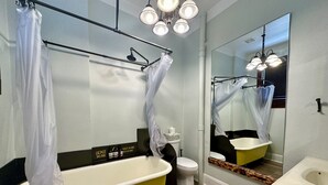 A bathroom with a yellow bathtub, a white toilet, a sink, and a large mirror. - Pet friendly 1bd/1b unit with full kitchen and dining area (Gainesville)