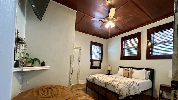 A bedroom with a bed, a ceiling fan, a wooden floor, and a window with blinds. - Pet friendly 1bd/1b unit with full kitchen and dining area (Gainesville)