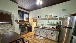 A compact kitchen with wooden flooring, a built-in oven, a stainless steel refrigerator, and a small island with a sink. - Pet friendly 1bd/1b unit with full kitchen and dining area (Gainesville)