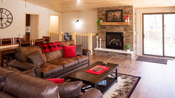Una sala de estar con chimenea de piedra, sofás de cuero y un comedor con mesa y sillas de madera.