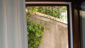 A doorway with a curtain, a stone wall, a lattice, and a rose bush.