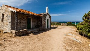 A stone building with a tiled roof, a white door, and a small porch.