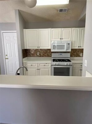 Kitchen features a stainless steel range hood, microwave, and sink with a faucet.