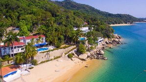 A coastal property with a swimming pool, beach access, and lush greenery.