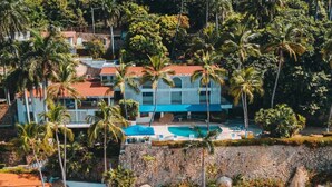 A resort with multiple buildings, a swimming pool, and palm trees.