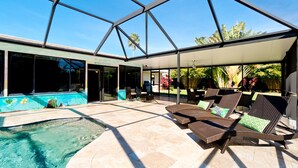 Ein Poolbereich im Innenbereich mit Liegestühlen und einer überdachten Terrasse mit Glas.