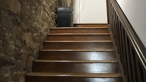 Een houten trap met een stenen muur aan één kant en een witte deur bovenin.