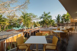 A terrace with yellow chairs and tables overlooking a pool and palm trees. - Casa Aakal Lagoon Front (Bacalar)