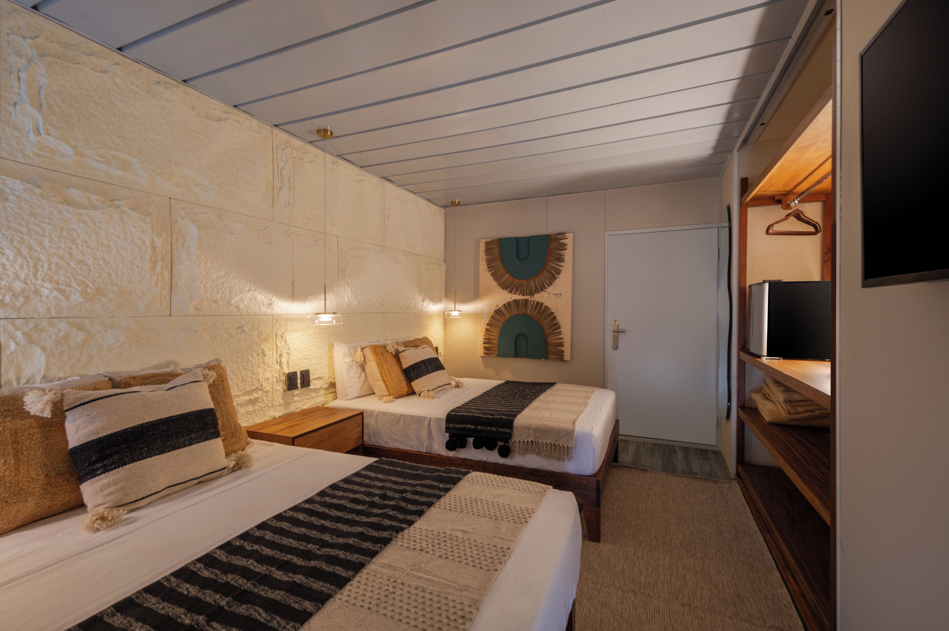 Een kamer met twee bedden, een televisie en een houten plank.