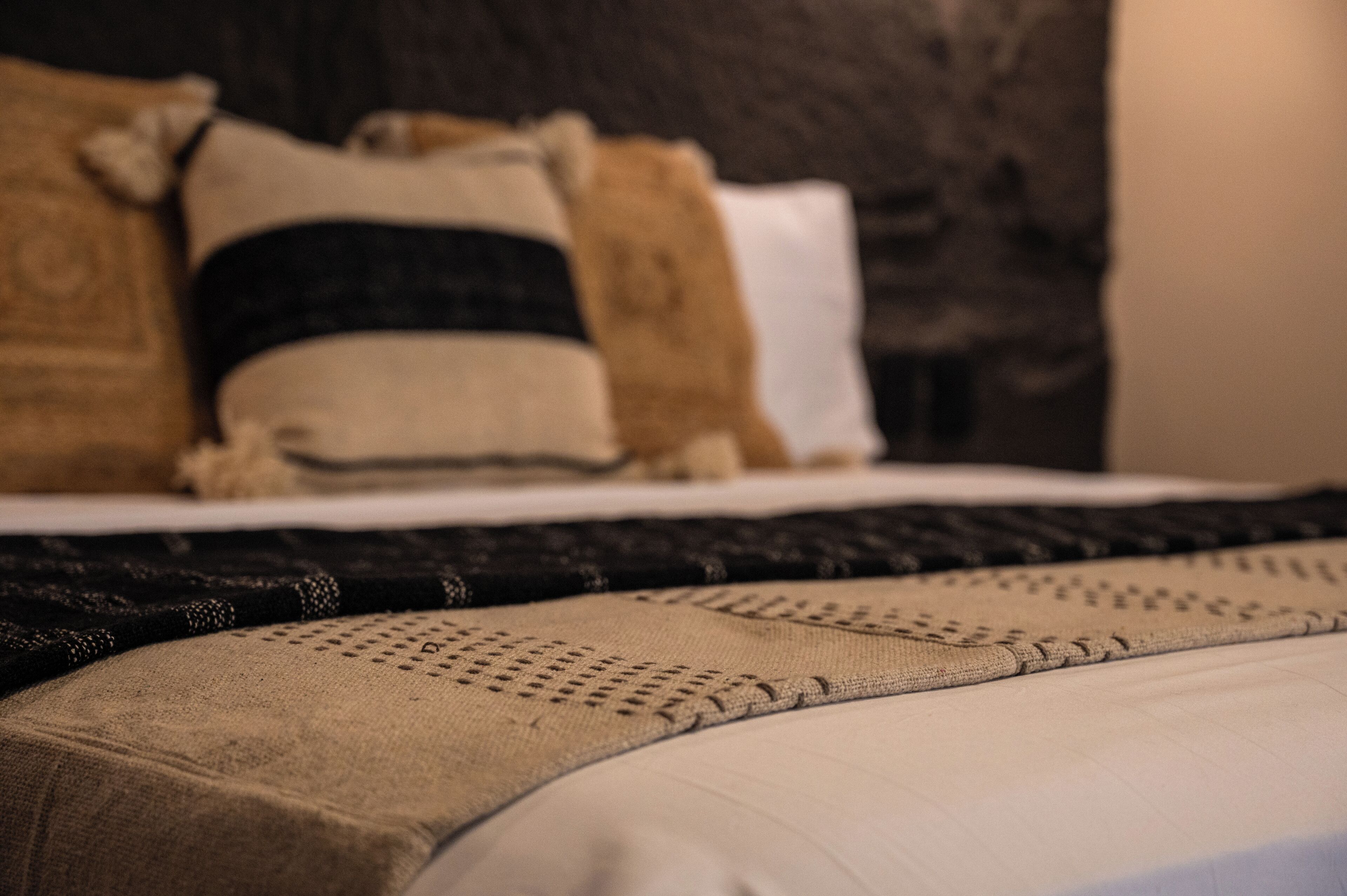 A bed with a dark headboard, multiple pillows, and a beige blanket.