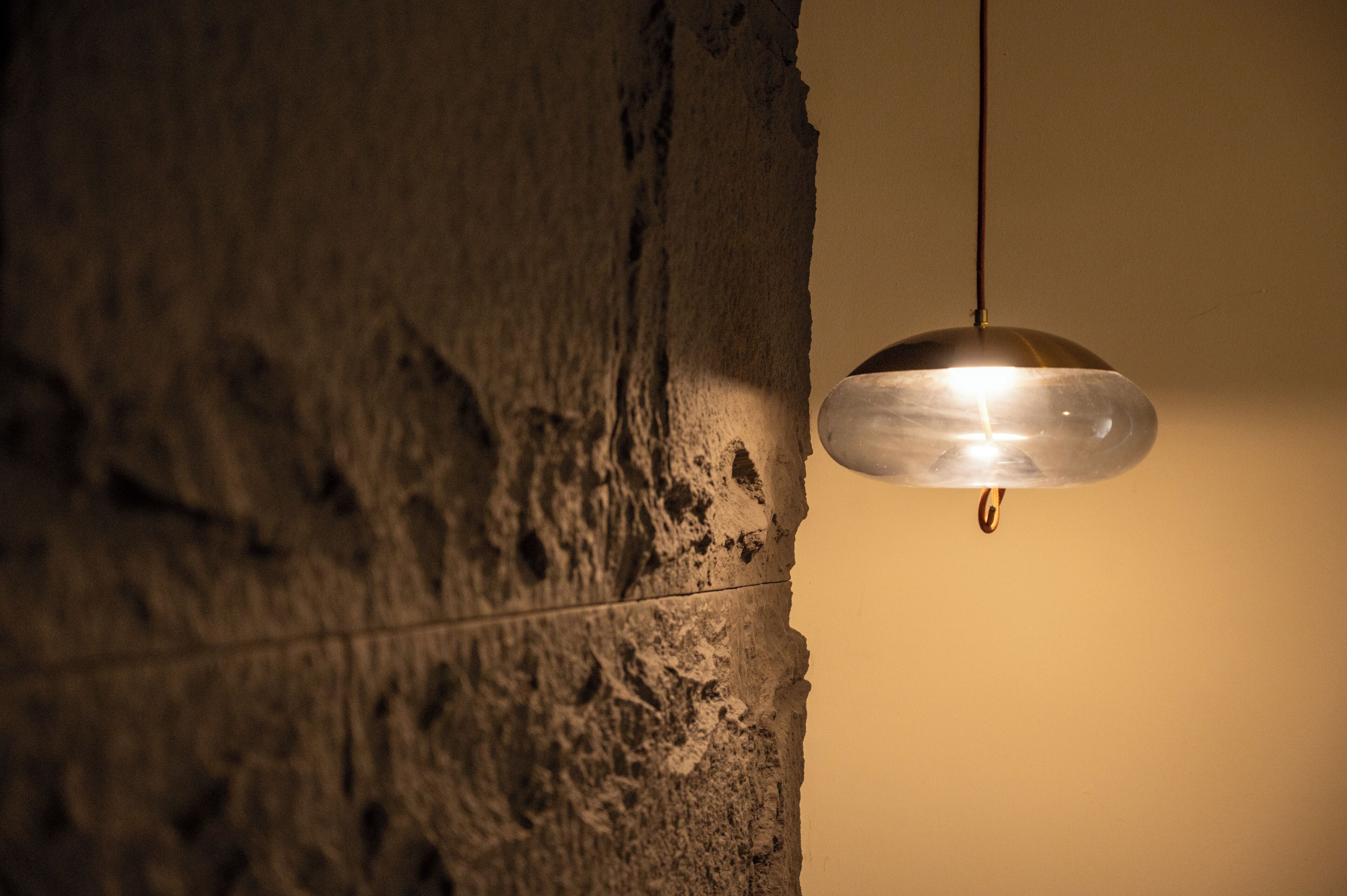 A pendant light fixture hanging from a textured wall.