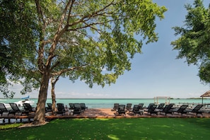 A beachside lounge with rows of black lounge chairs and a wooden deck overlooking the ocean. - Casa Aakal Lagoon Front (Bacalar)