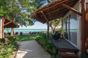 Una terraza de madera con sillas de descanso y una estructura de techo de paja con vista al mar.
