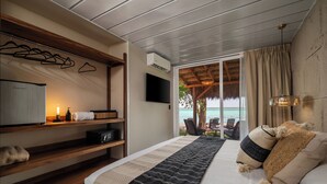 Un dormitorio con cama, mesitas de noche, televisor y vista al océano.