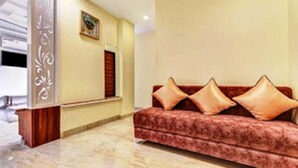 A reception area with a red sofa, a wooden reception desk, and a marble floor. - Hotel Manik (Chhatrapati Sambhajinagar)