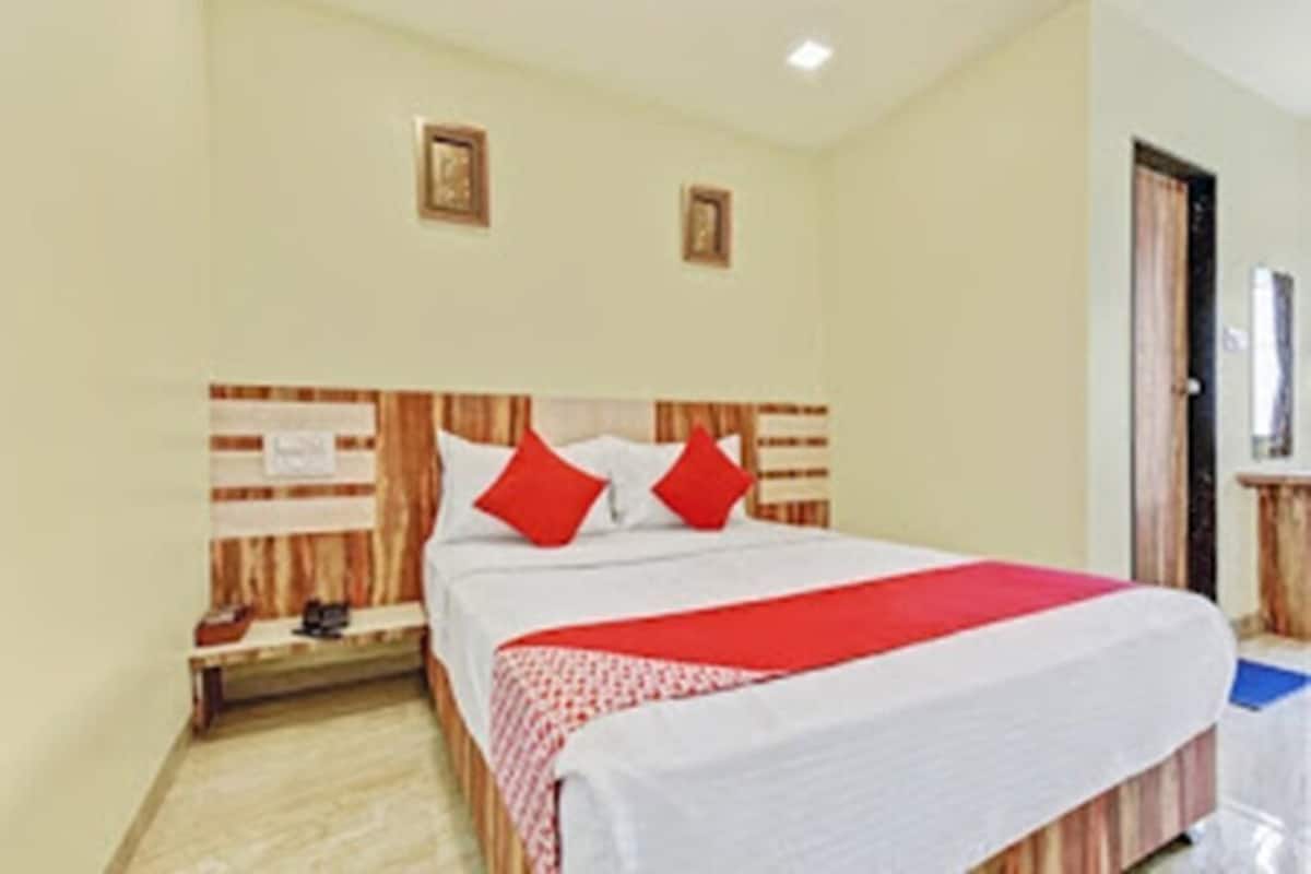 A hotel room with a bed, wooden headboard, and a nightstand.