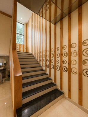 A staircase with wooden handrails and a wall with circular patterns. - Hotel Manik (Chhatrapati Sambhajinagar)