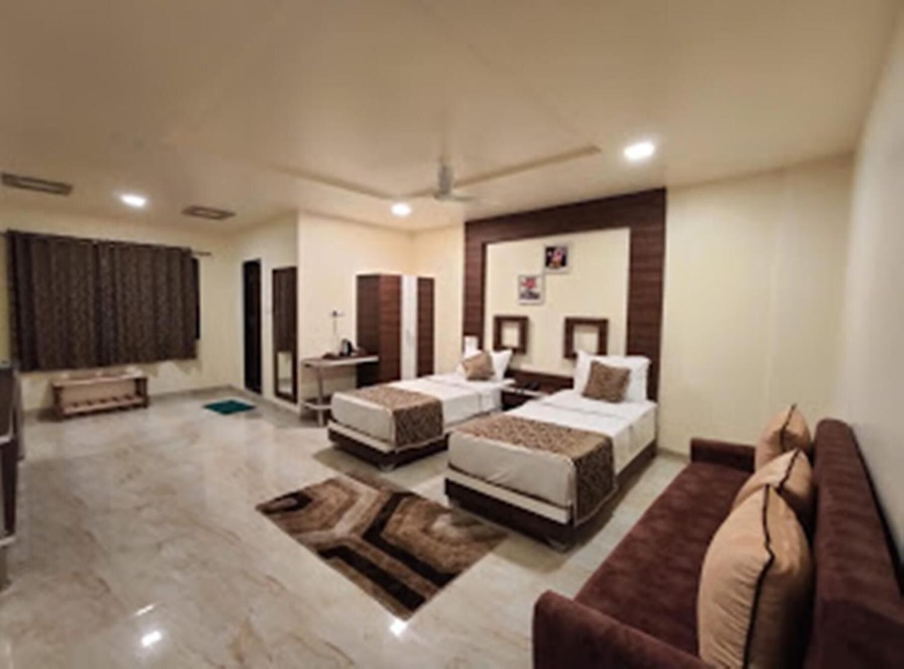 Habitación de hotel con dos camas, un sofá, un escritorio y un ventanal grande.