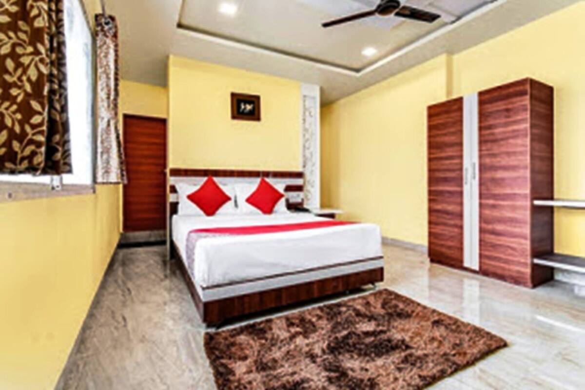 A bedroom with a bed, a ceiling fan, a wardrobe, and a carpet.